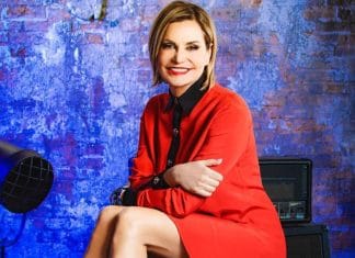 Simona Ventura in abito rosso sorride alla telecamera